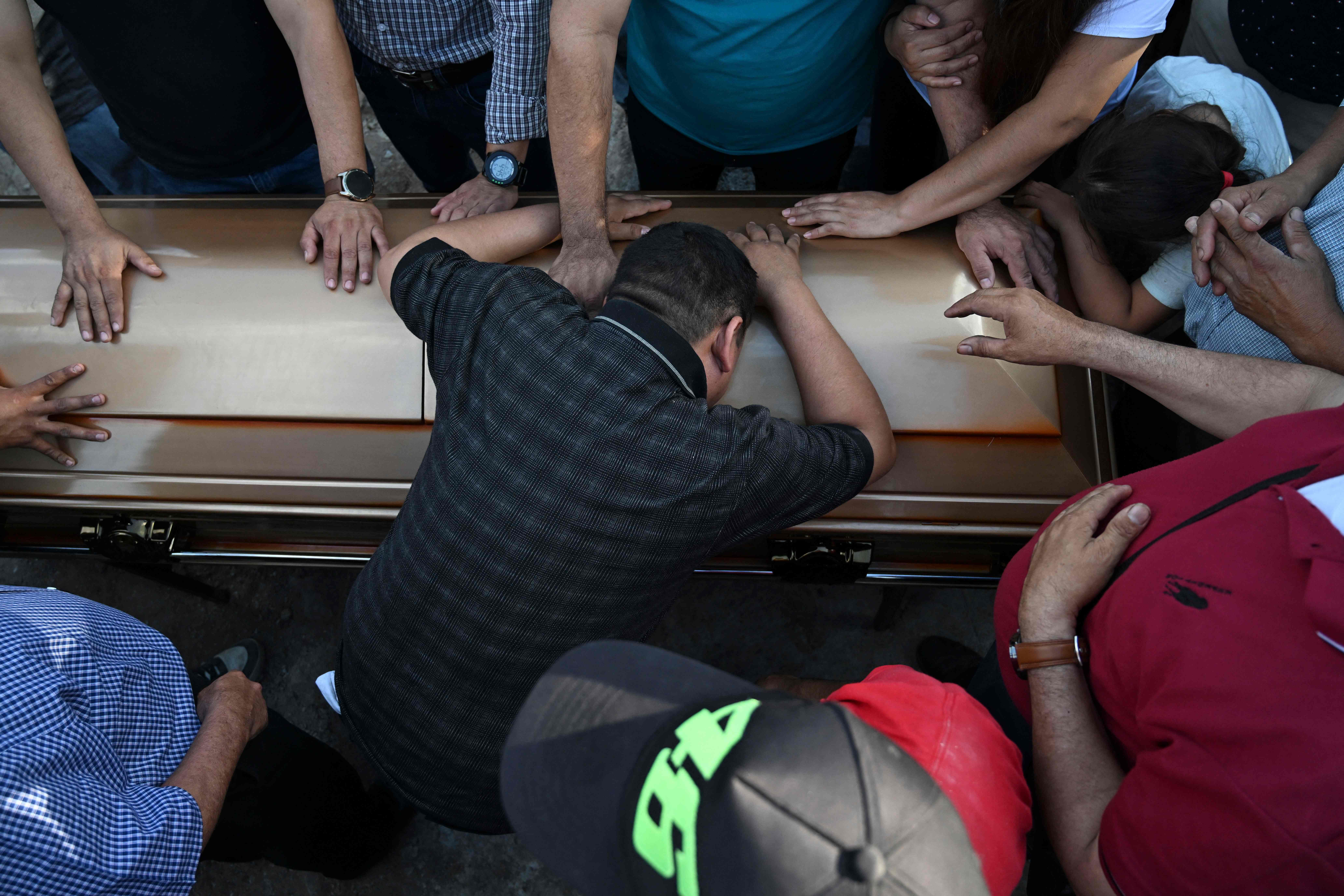 Un hombre llora sobre el ataúd de una de las víctimas en el cementerio de la aldea Santo Domingo Los Ocote. (Foto: Prensa Libre: AFP)