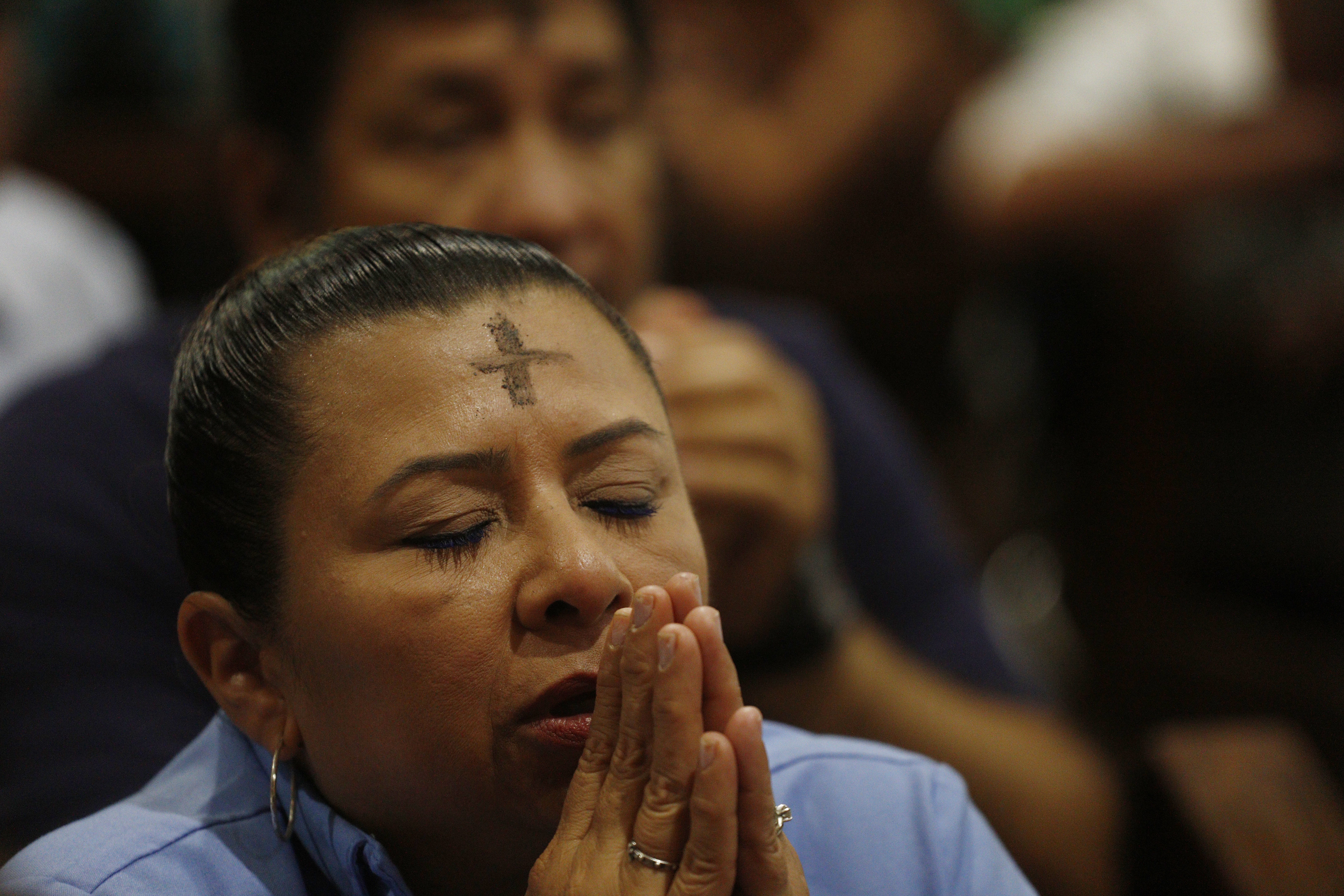  Una mujer reza en una misa durante una celebración del Miércoles de Ceniza.  (Foto Prensa Libre: EFE)