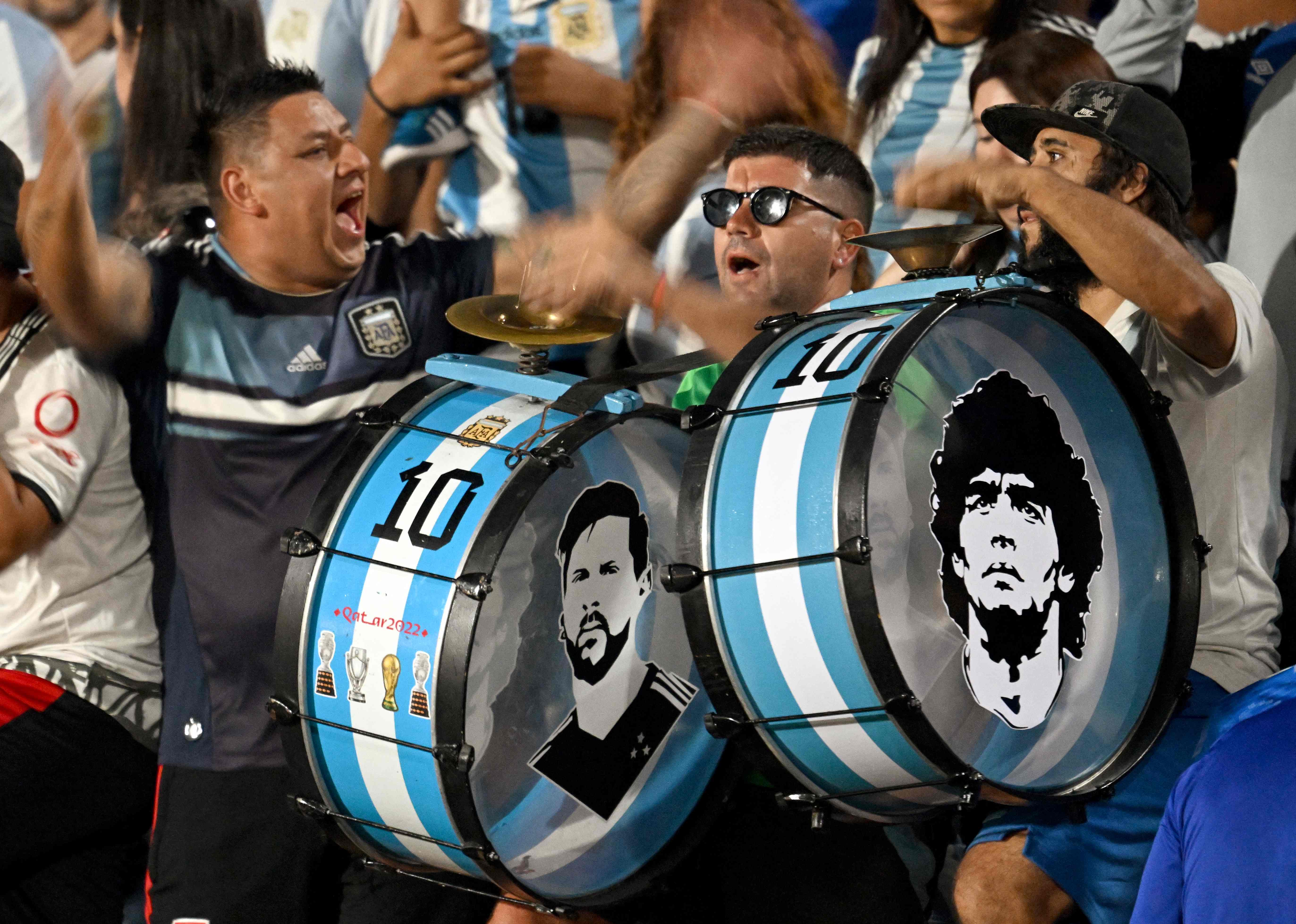 Los rostros de las leyendas argentinas Diego Armando Maradona y Lionel Messi son plasmados en los bombos de la barra argentina en el estadio. (Foto Prensa Libre: AFP)