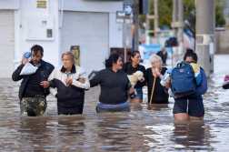People walk through flooded waters the day after a heavy storm in Bahia Blanca, 600 km south of Buenos Aires on March 8, 2025. At least ten people died and more than 1,000 were evacuated in the Argentine port city of Bahia Blanca as torrential rains flooded homes and hospitals, destroyed roads and forced authorities to cut the power. (Photo by PABLO PRESTI / AFP)