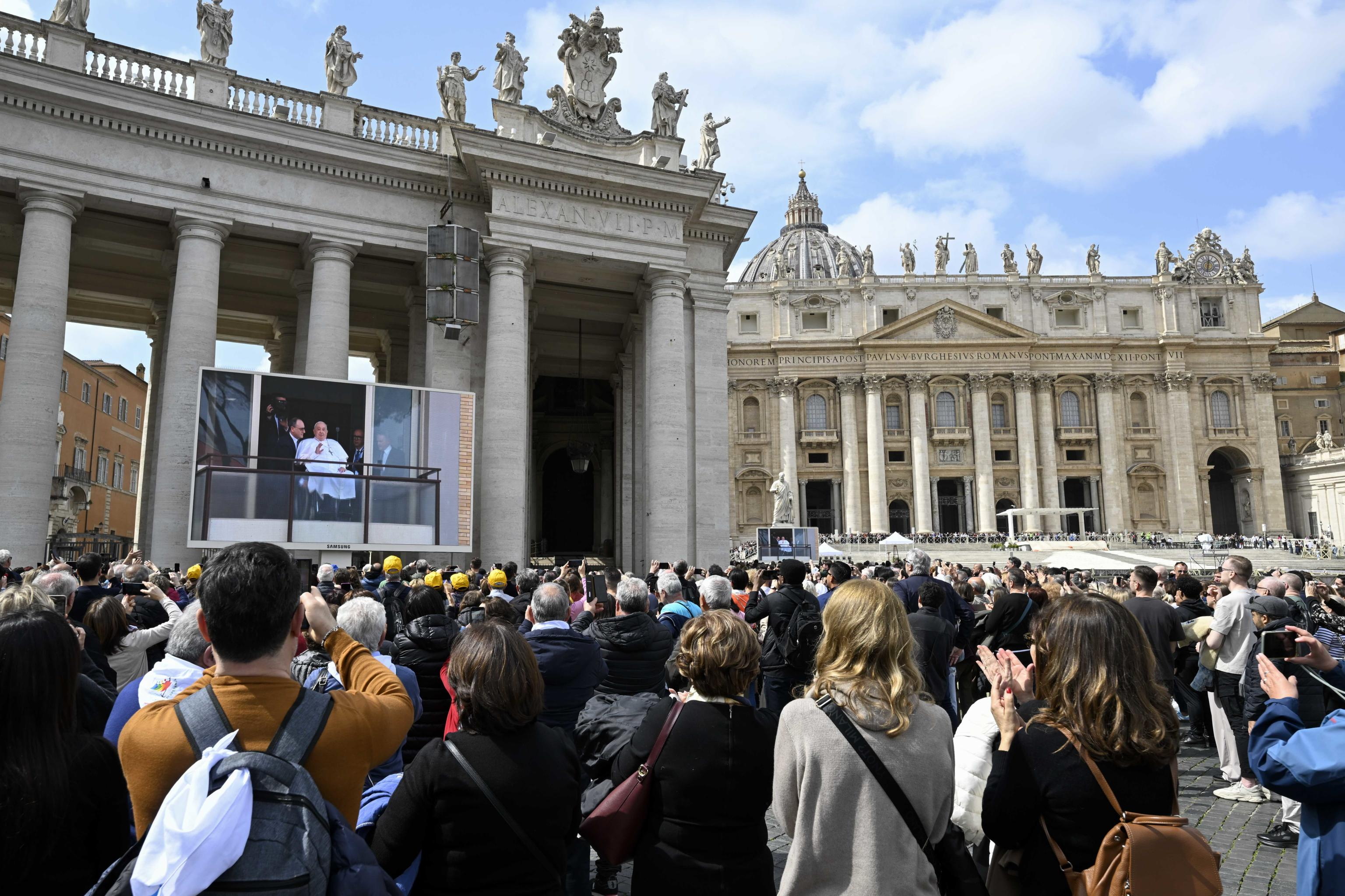 Fieles se reúnen en la Plaza de San Pedro de la Ciudad del Vaticano para observar desde una pantalla cómo el papa Francisco bendijo a los asistentes desde el balcón del hospital Gemelli. (Foto Prensa Libre: EFE)