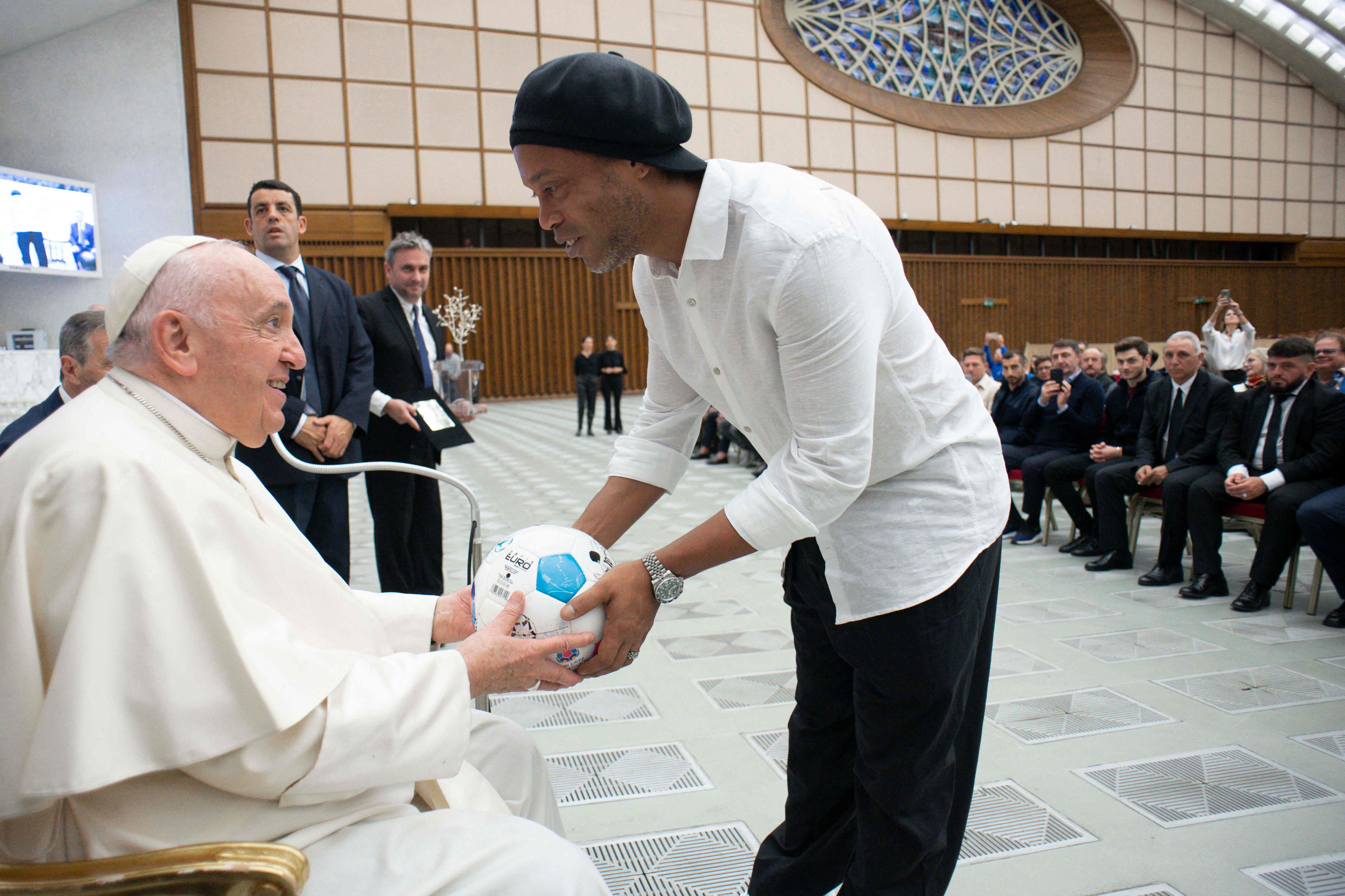 El exjugador brasileño Ronaldinho, entrega un balón al papa Francisco durante una audiencia con los participantes de un amistoso "partido por la paz" en memoria del fallecido jugador argentino Diego Maradona, el 14 de noviembre de 2022 en el Aula Pablo VI del Vaticano. (Foto Prensa Libre: AFP)