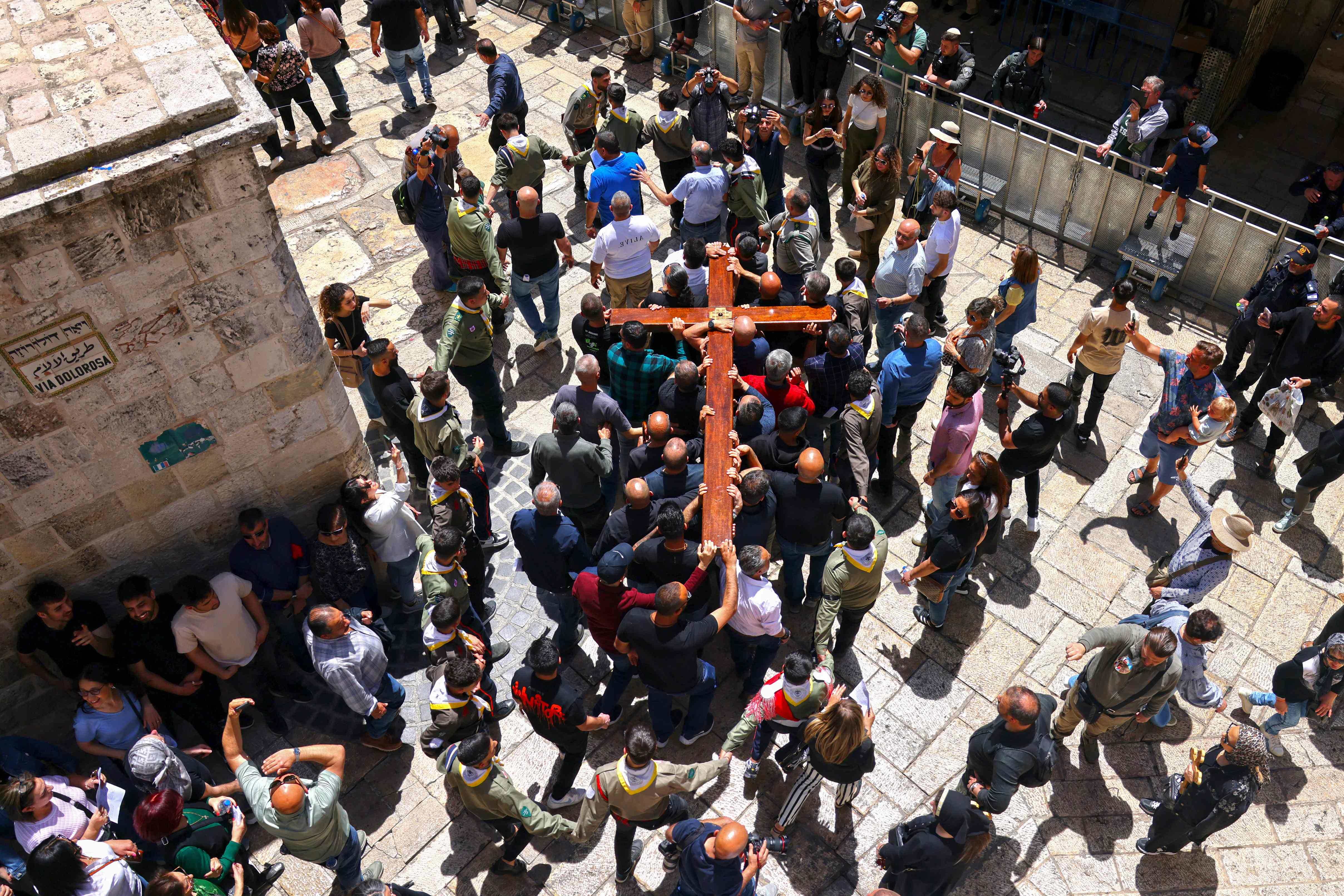 Christians carrying a large wooden cross walk through the old city of Jerusalem on the way to the Holy Sepulcher during the Orthodox Procession of Good Friday, on April 18, 2025.