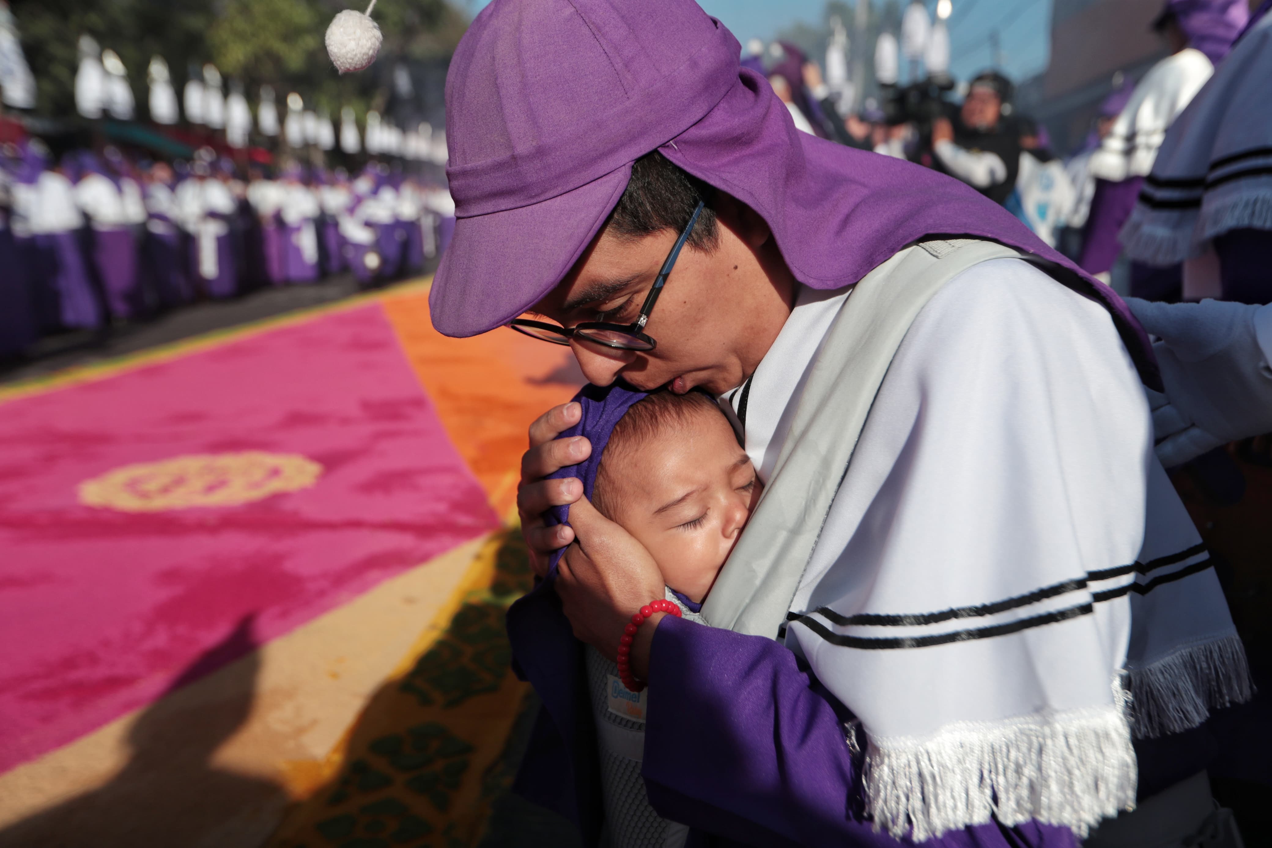 Un cucurucho besa a su hija antes de cargar el anda de Jesús de Candelaria, en un emotivo gesto de fe y amor familiar. (Foto Prensa libre: Esbin García)