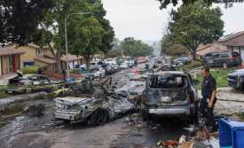 TOPSHOT - Investigators look through the site where a small plane crashed on a San Diego, California, residential street on May 22, 2025. The Federal Aviation Authority said a Cessna 550 crashed at around 3:45 am local time. The neighborhood is close to the Montgomery-Gibbs Executive Airport. The crash left a "gigantic debris field" and damaged some 15 homes and parked cars, ABC News quoted the San Diego assistant fire chief as saying. (Photo by Sandy Huffaker / AFP)