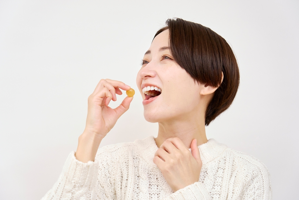 Mujer asiática con la gota de la tos en el fondo blanco