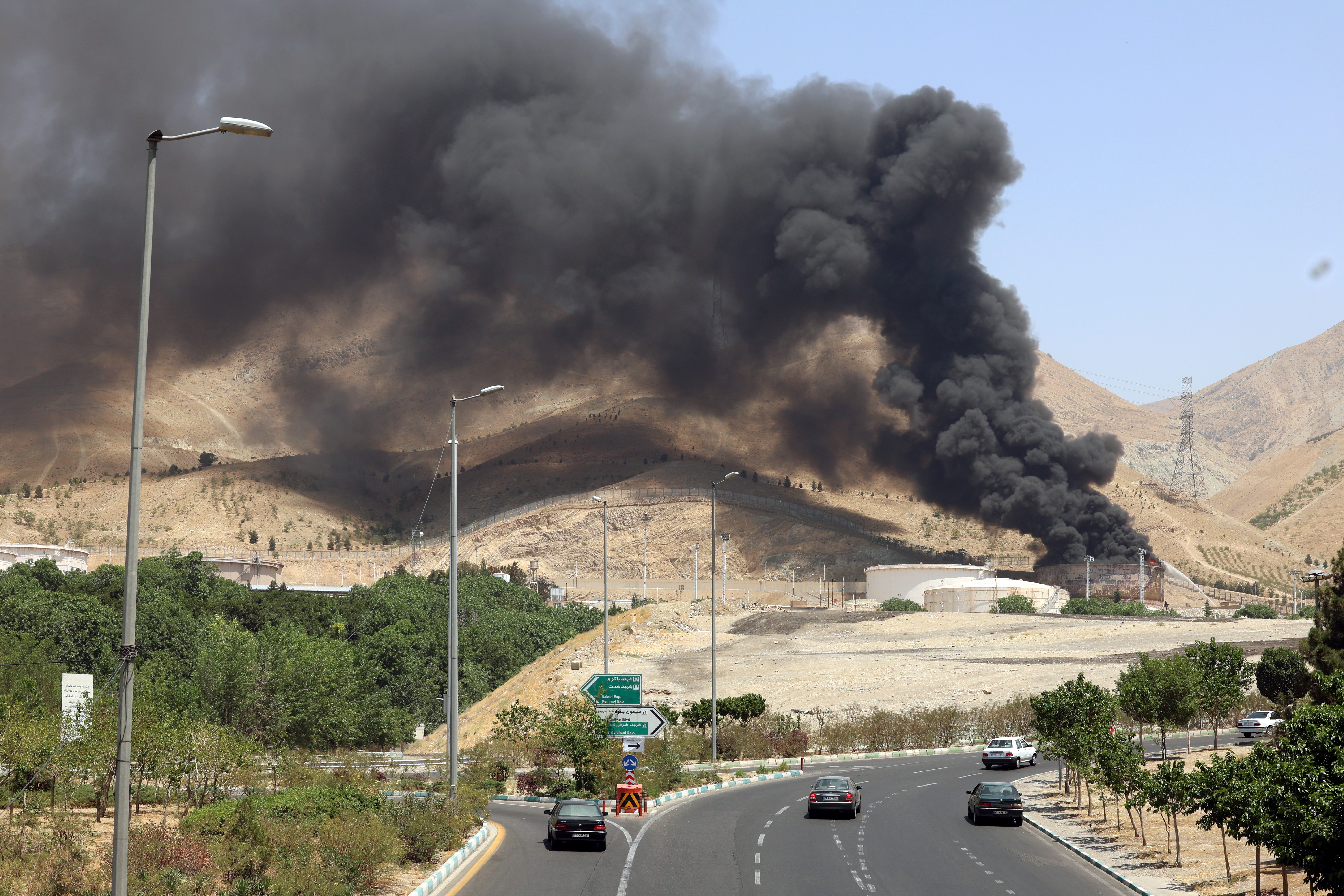 Vehículos circulan por una autopista mientras se eleva humo al fondo desde una refinería de petróleo, al noroeste de Teherán, Irán. (Foto Prensa Libre: EFE)
