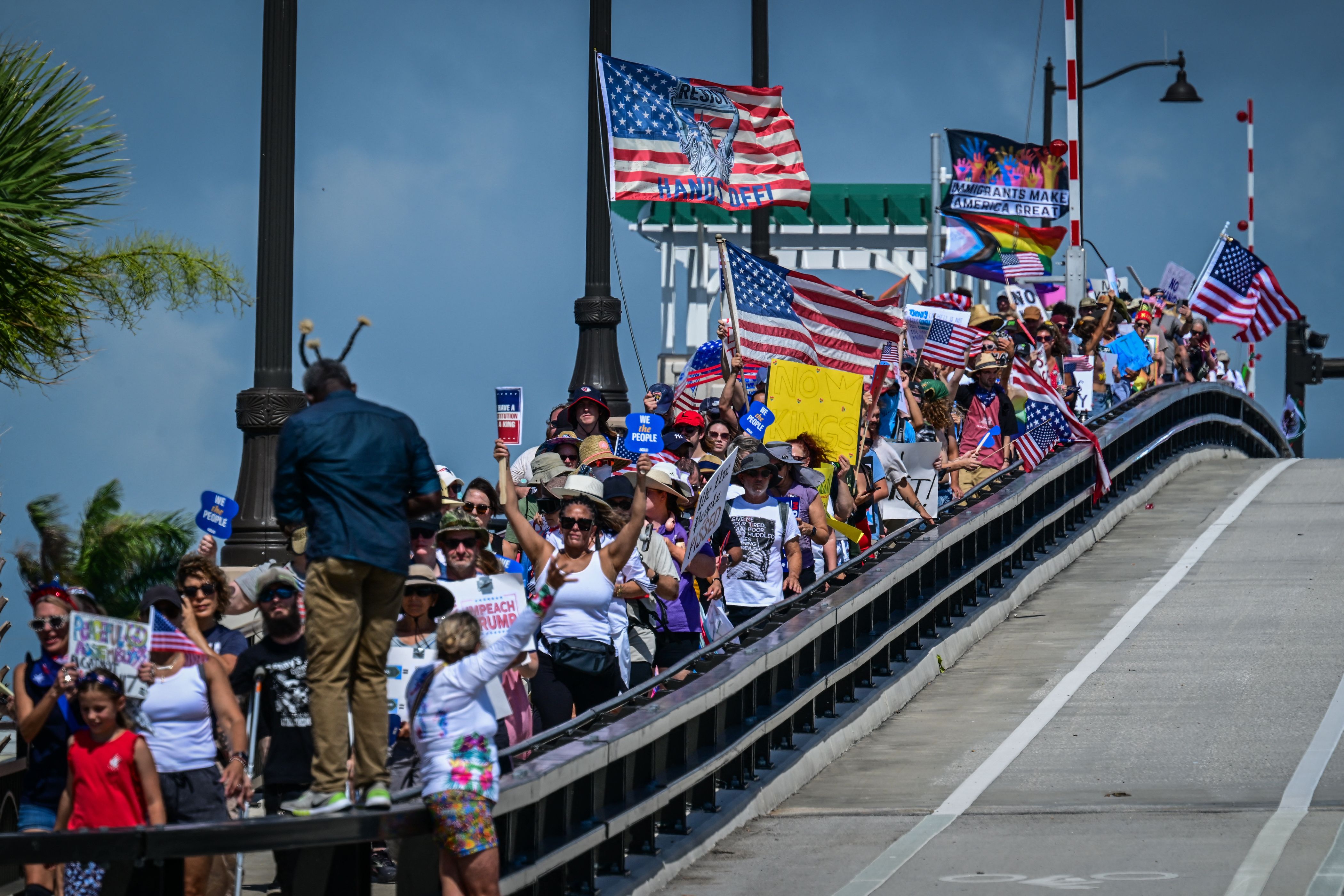 Manifestantes con pancartas y banderas estadounidenses protestan contra la administración Trump en West Palm Beach, Florida. (Foto Prensa Libre: AFP)
