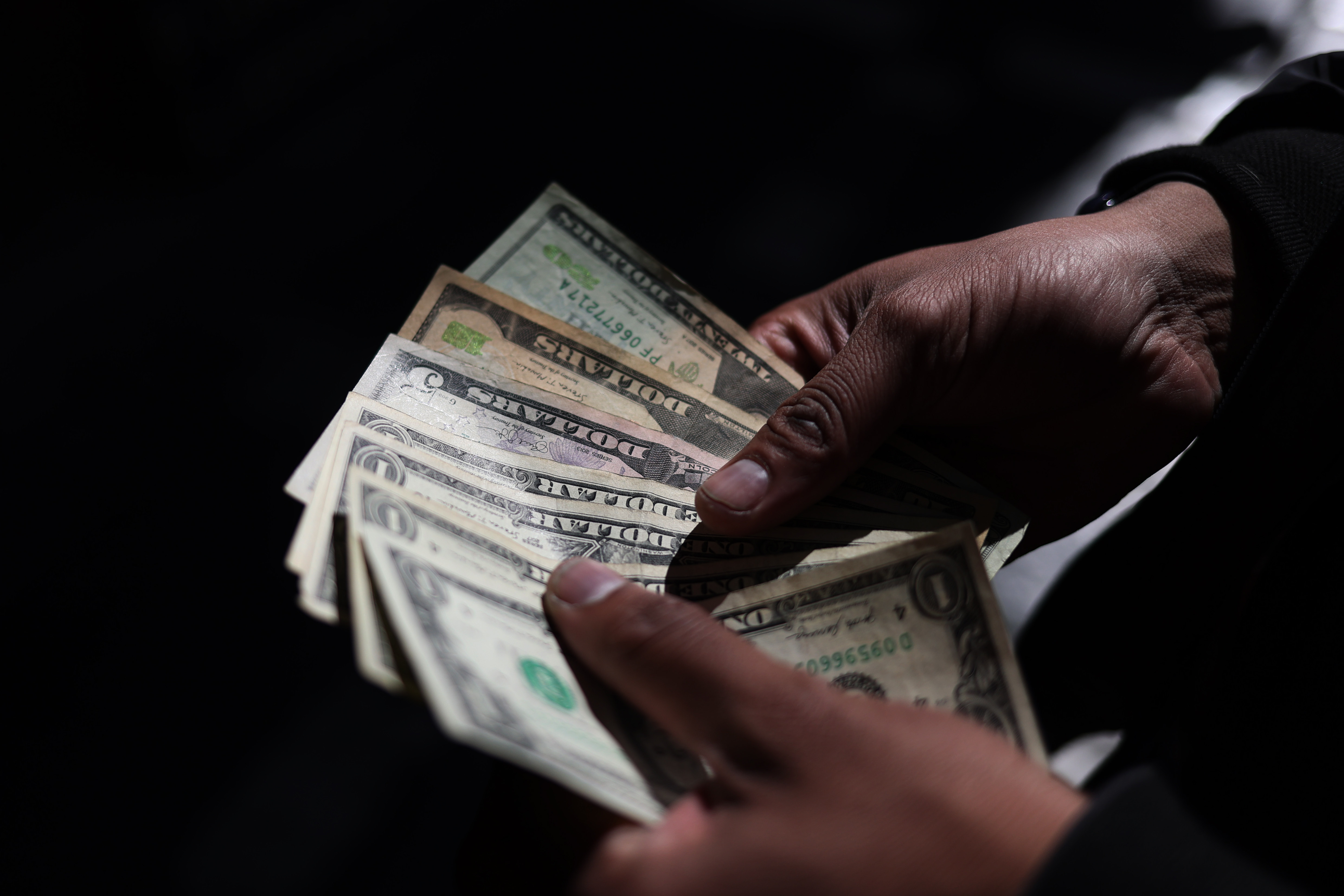 AME9747. LA PAZ (BOLIVIA), 13/08/2025.- Fotografía de archivo del 1 de julio de 2024 de una persona contando dólares en La Paz (Bolivia). El próximo Gobierno de Bolivia que sea elegido en los comicios de este 17 de agosto recibirá un país con persistentes problemas como la falta de dólares y combustibles, bajo crecimiento y una inflación acumulada de 16,92 % que para algunos expertos son síntomas de una crisis por el agotamiento del modelo defendido por el presidente Luis Arce. EFE/ Luis Gandarillas / ARCHIVO