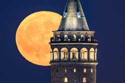 TOPSHOT - The Sturgeon moon is seen rising over Galata Tower in Istanbul, on August 9, 2025. (Photo by Yasin AKGUL / AFP)