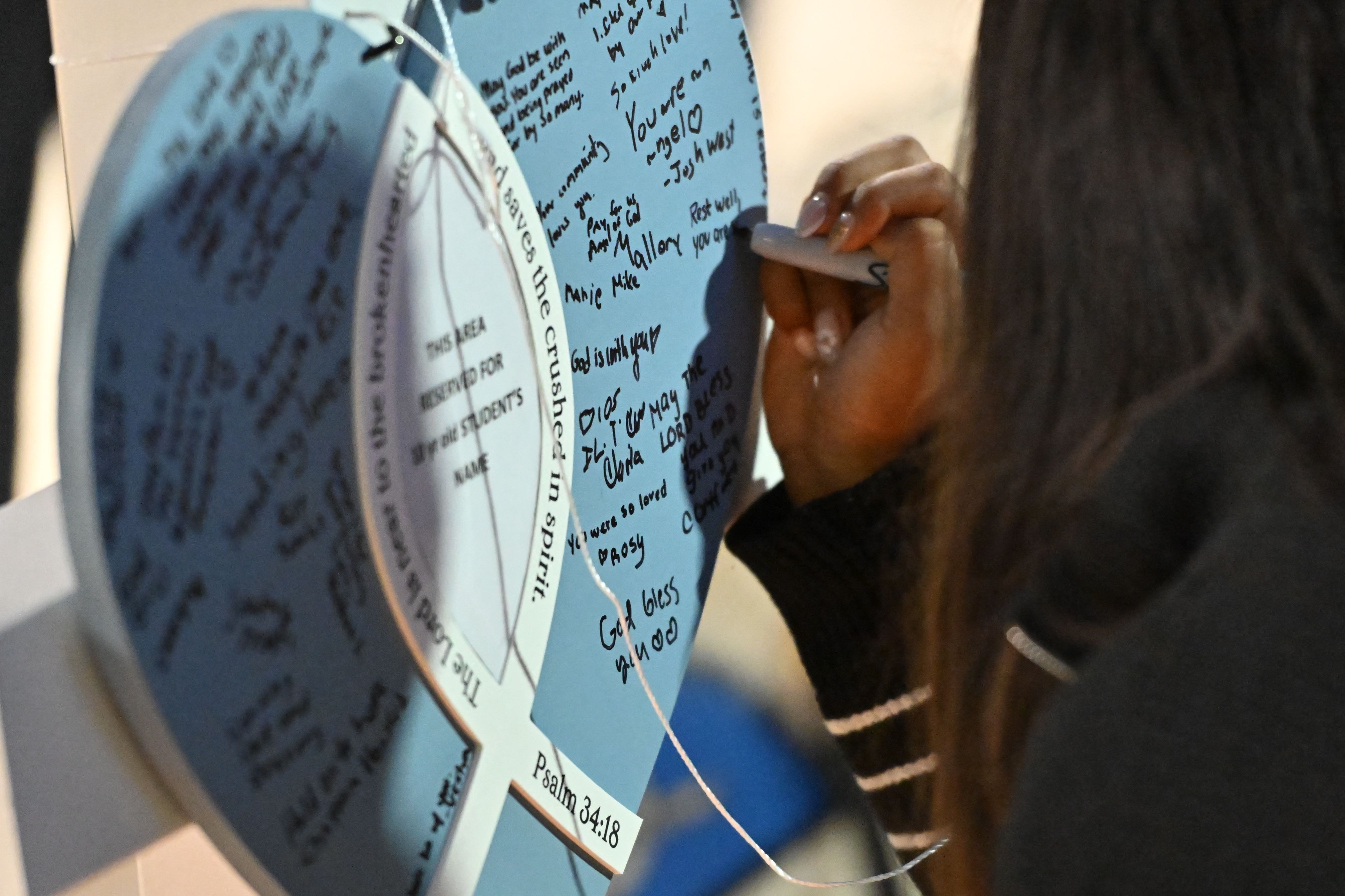 Personas escriben mensajes de condolencia en cruces en memoria de las víctimas del tiroteo. (Foto Prensa Libre: AFP)