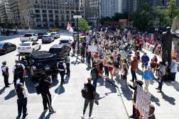 Police officers stand on the street as protesters hold signs during a rally outside Trump Tower on Labor Day in Chicago, Illinois, September 1, 2025. (Photo by KAMIL KRZACZYNSKI / AFP)