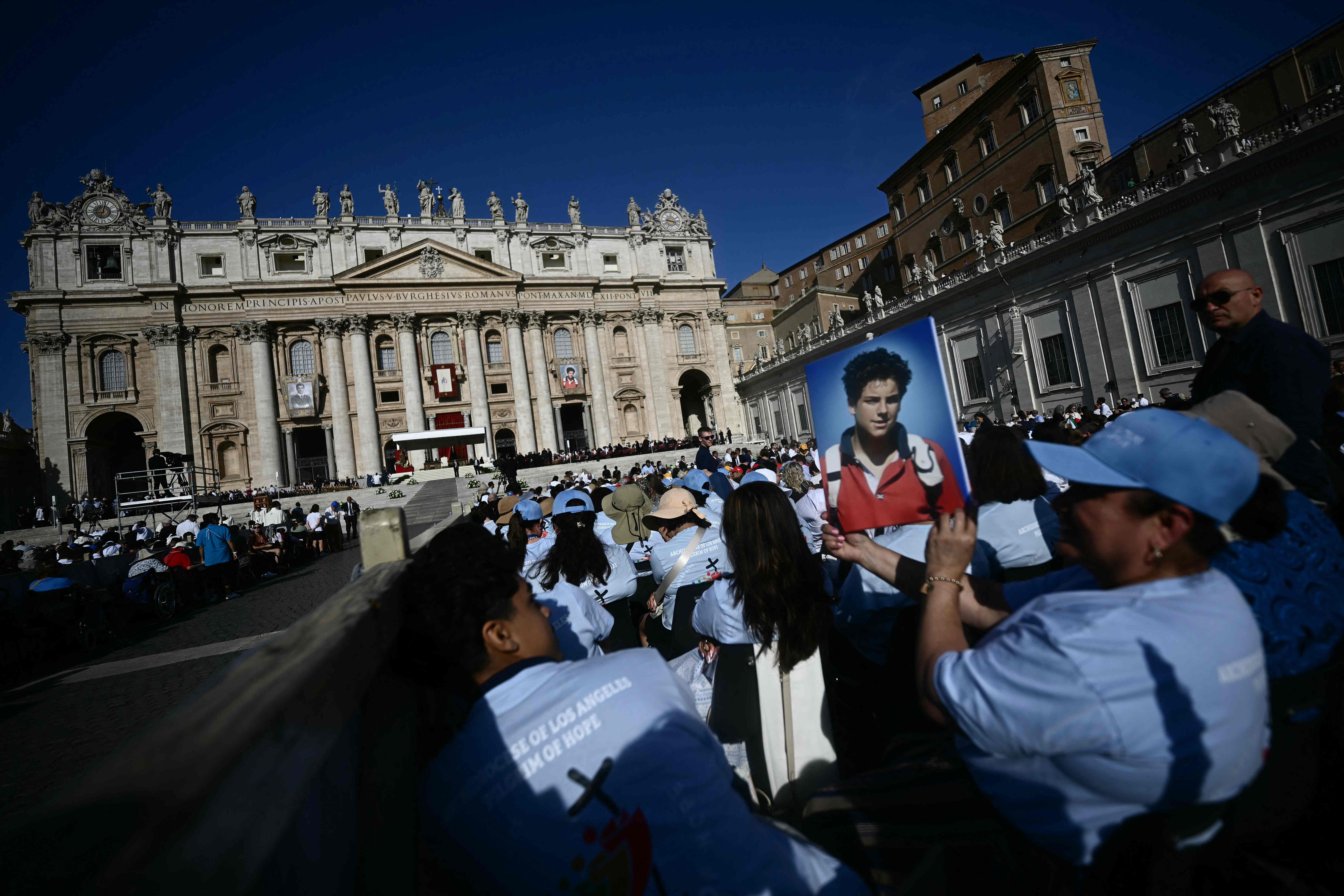 Un fiel sostiene un retrato del difunto adolescente Carlo Acutis frente a la Basílica de San Pedro, antes de la Santa Misa y la ceremonia de canonización de los beatos Carlo Acutis y Pier Giorgio Frassati en la Plaza de San Pedro del Vaticano.  (Foto Prensa Libre: AFP)