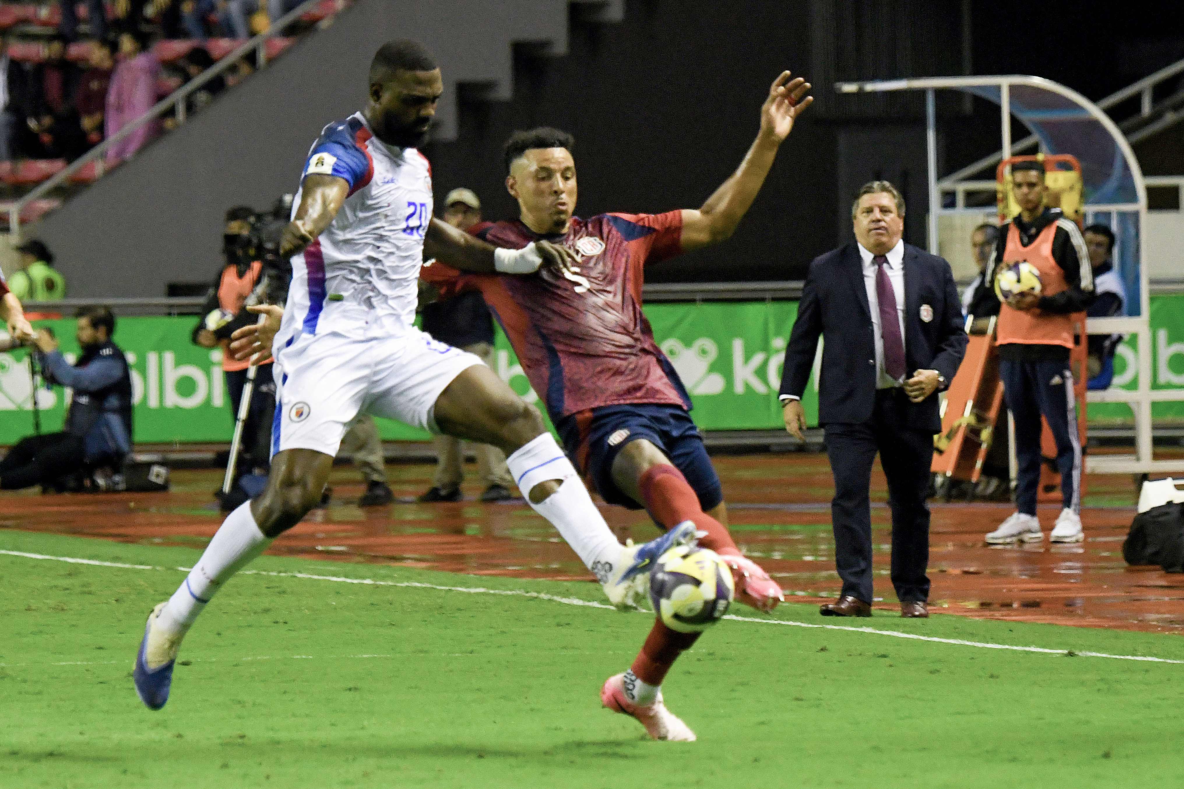 El delantero 20 de Haití, Pierrot, y el defensor 05 de Costa Rica, Julio Cascante, luchan por el balón en el duelo Costa Rica y Haití por las eliminatorias de Concacaf. 