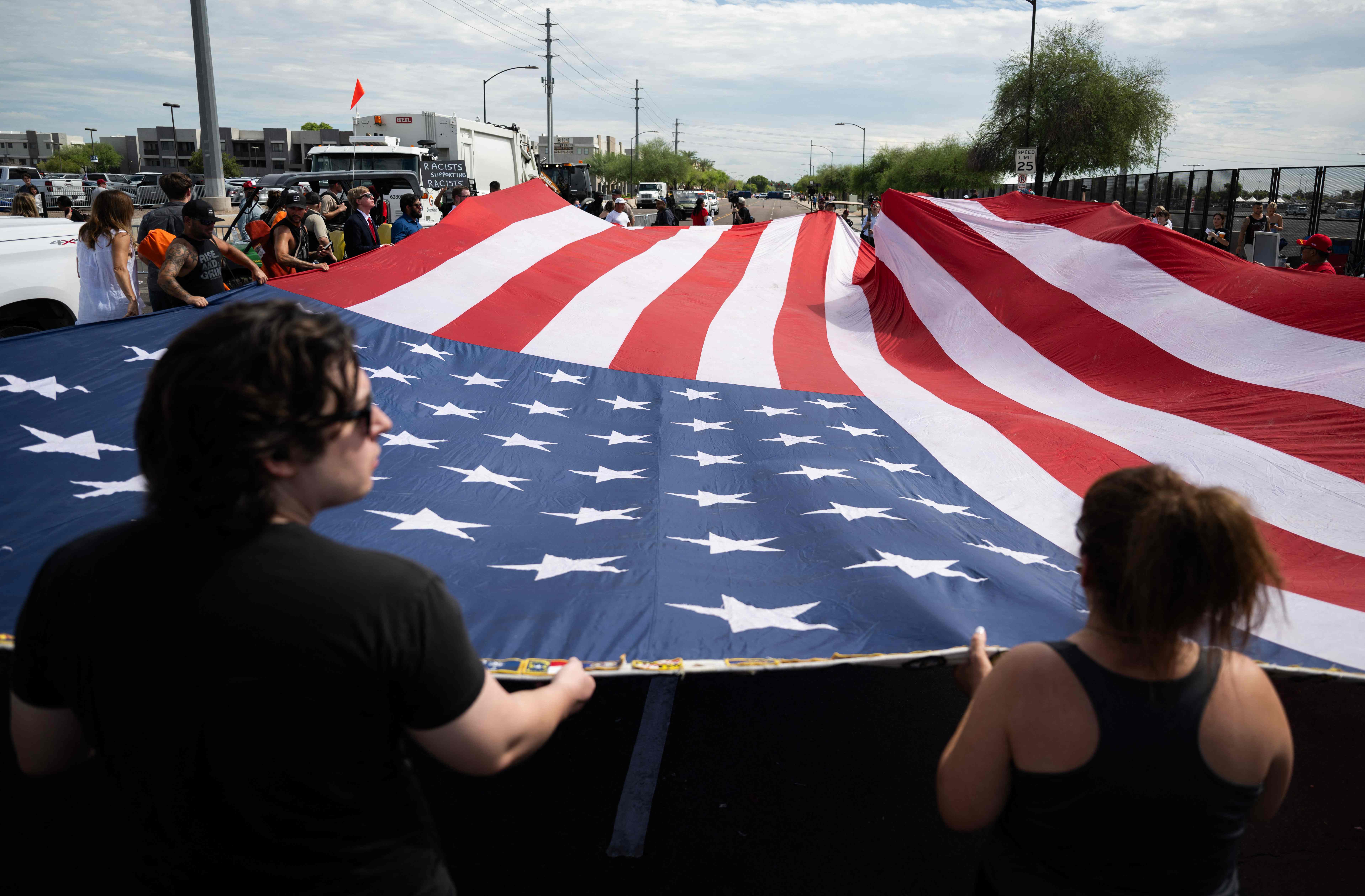 Supporters of Charlie Kirk and US President Donald Trump hold a large US flag outside State Farm Stadium during the public memorial service for right-wing activist Charlie Kirk in Glendale, Arizona, on September 21, 2025. (Photo by ANDREW CABALLERO-REYNOLDS / AFP)