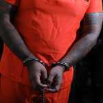 Brazos y manos esposadas de un reo con traje anaranjado, mientras es trasladado junto a otros miembros de la MS-13 y Barrio 18 al centro de detención de máxima seguridad en Escuintla.