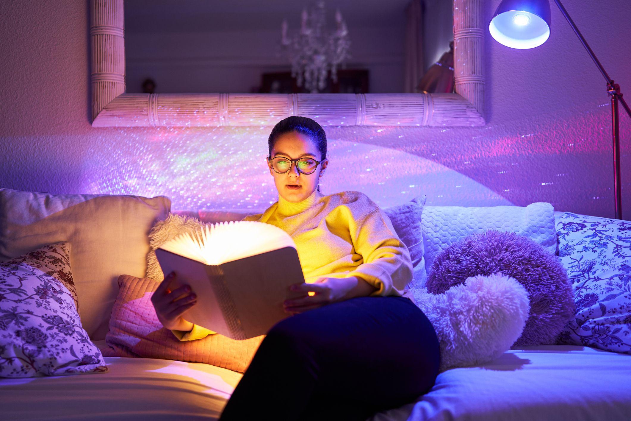 Mujer de lentes leyendo libro iluminado.