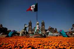 View of cardboard and papier-mâché giant skeletons and xoloitzcuintles (Mexican hairless dog) amid marigold (tagetes erecta) flowers during the inauguration of a mega offering ahead of the Day of the Dead, at the Zocalo square in Mexico City, Mexico on October 26, 2025. (Photo by Rodrigo Oropeza / AFP)
