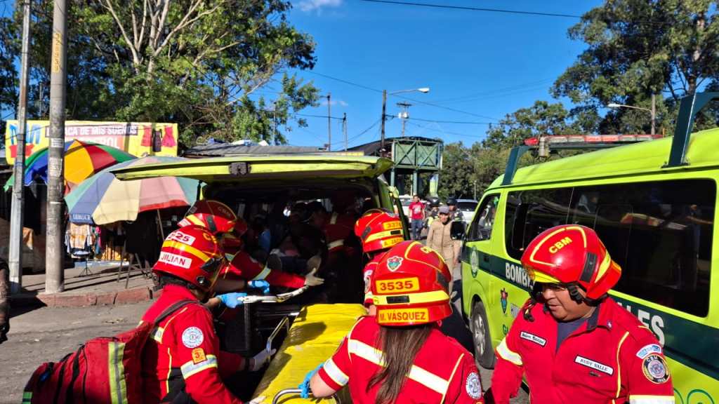 Técnicos en urgencias médicas de Bomberos estabilizan a dos hombres heridos por arma de fuego en la zona 12 de Ciudad de Guatemala.