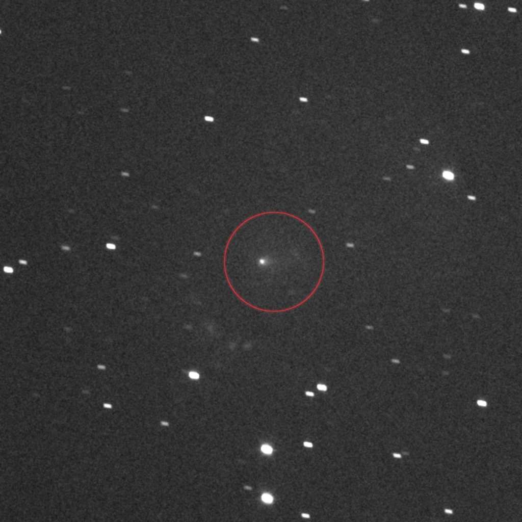 el cometa interestelar 3I/ATLAS, rodeado por un círculo en el centro, captado por la cámara en blanco y negro LLORRI a bordo de la sonda Lucy de la NASA. La imagen se creó apilando una serie de fotografías tomadas el 16 de septiembre de 2025, cuando el cometa se dirigía a gran velocidad hacia Marte y la sonda Lucy se encontraba a 386 millones de kilómetros de 3I/ATLAS. (Foto Prensa Libre: AFP)