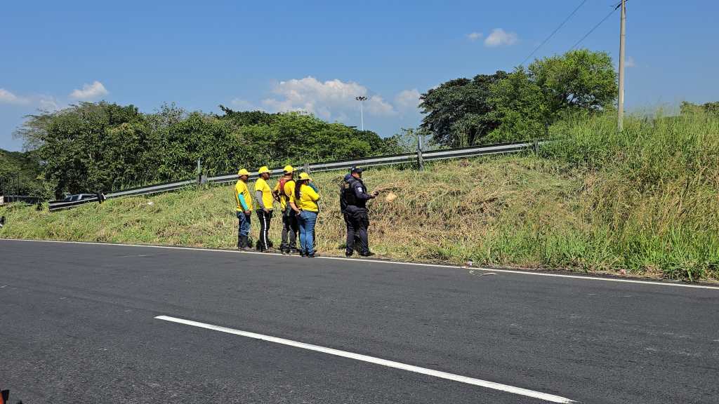Agentes de la PNC y trabajadores de Covial permanecen en la orilla de la carretera, cerca del área verde donde se encontró un cuerpo.