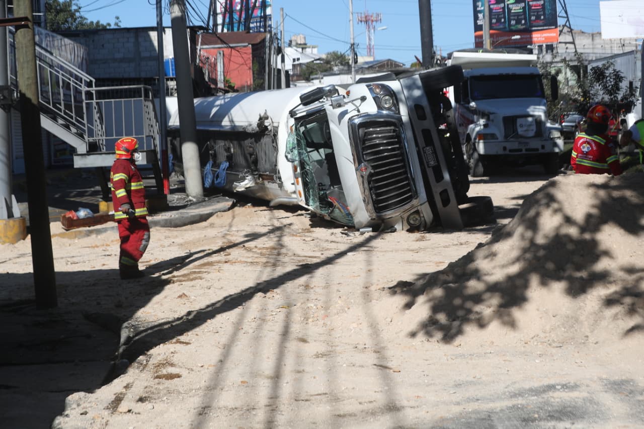 Bombero inspecciona la parte frontal de la cisterna volcada con tierra esparcida alrededor.