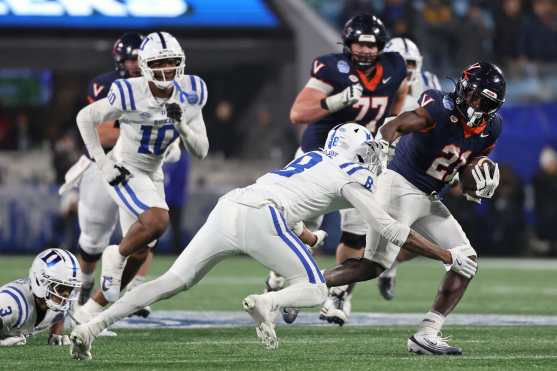 CHARLOTTE, NORTH CAROLINA - DECEMBER 06: Harrison Waylee #21 of the Virginia Cavaliers is tackled by Dashawn Stone #8 of the Duke Blue Devils during the fourth quarter in the 2025 ACC Football Championship at Bank of America Stadium on December 06, 2025 in Charlotte, North Carolina.   David Jensen/Getty Images/AFP (Photo by David Jensen / GETTY IMAGES NORTH AMERICA / Getty Images via AFP)