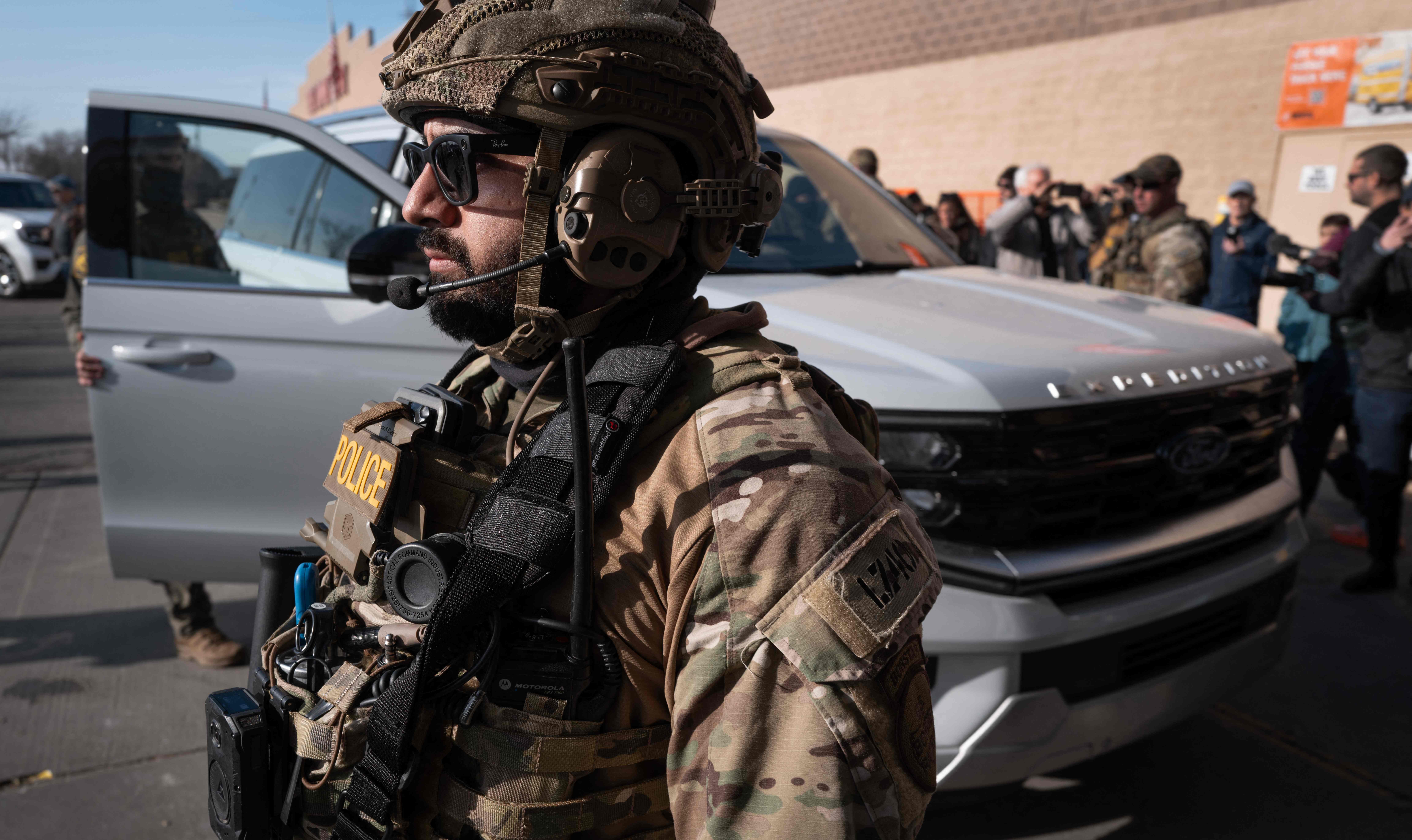 EVANSTON, ILLINOIS - DECEMBER 17: A Border Patrol agent stands guard as two men who are suspected of being undocumented are taken into custody at a Home Depot store on December 17, 2025 in Evanston, Illinois. The agents made apprehensions of suspected undocumented immigrants as they patrolled through Chicago and several nearby suburbs.   Scott Olson/Getty Images/AFP (Photo by SCOTT OLSON / GETTY IMAGES NORTH AMERICA / Getty Images via AFP)