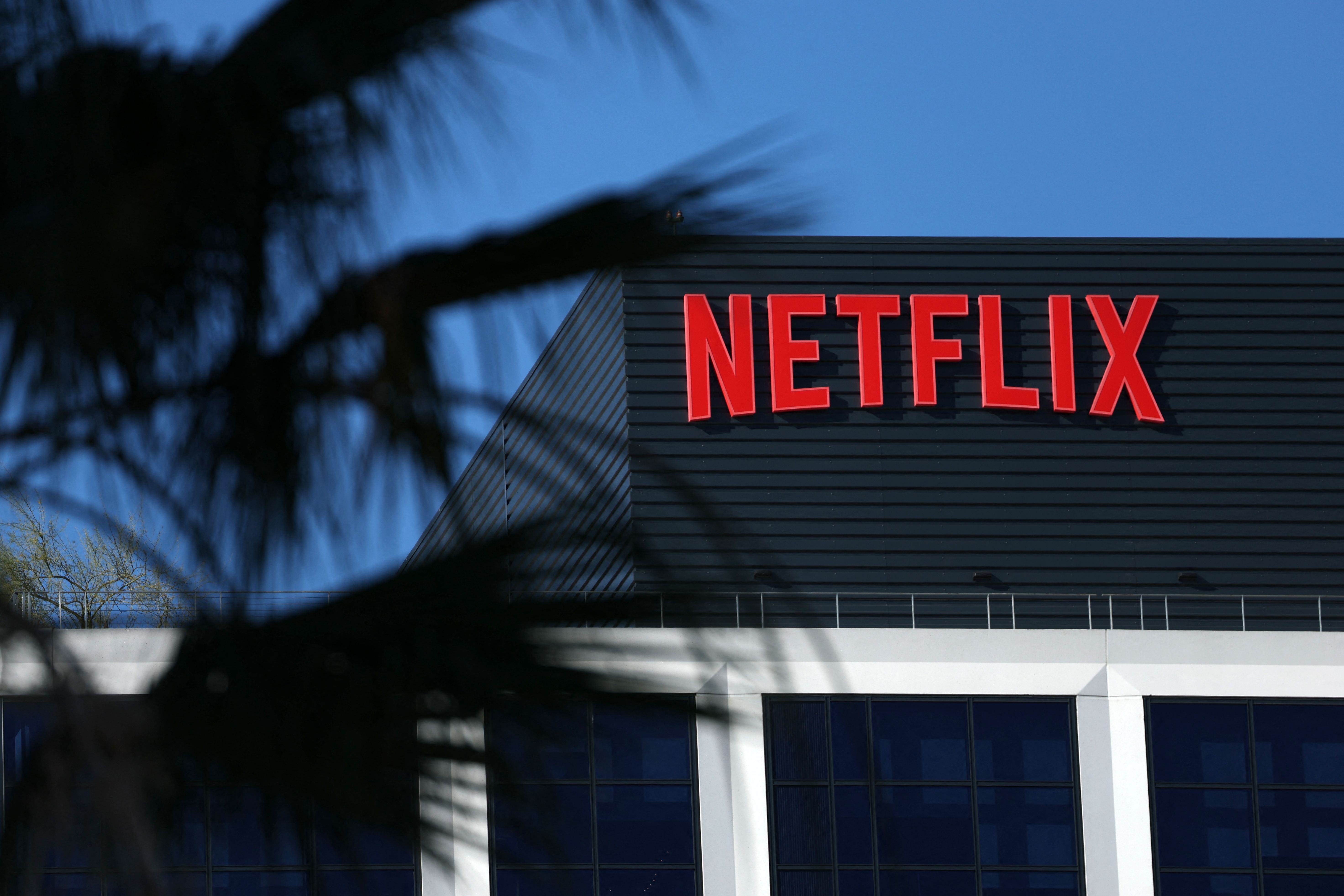 The Netflix logo is pictured at the companys Hollywood studio offices at Sunset Bronson Studios in Los Angeles, California on December 5, 2025. Streaming giant Netflix said December 5, 2025 it will buy film and television studio Warner Bros. Discovery for nearly $83 billion, the entertainment industry's biggest consolidation deal this decade. The acquisition gives Netflix access to a vast film catalog as well as the prestigious streaming service HBO Max. (Photo by Patrick T. Fallon / AFP)