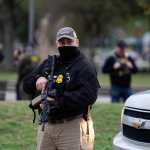 A US Customs and Border Patrol agent stands guard as Commander Gregory Bovino conducts interviews with residents during operations at a park in Metairie, Louisiana, on December 5, 2025. The US Department of Homeland Security announced on December 3 it has launched a federal immigration enforcement operation, named "Operation Catahoula Crunch," in the New Orleans, Louisiana, area. (Photo by Adam GRAY / AFP)