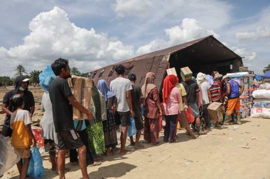 Residents queue to receive basic food supplies and drinking water at a logistics post built by local residents to accommodate incoming aid, in Lintang Bawah village in Aceh Tamiang, Northern Sumatra, on December 11, 2025. Regions hit by floods that killed hundreds in Indonesia were suffering from food and medical shortages, authorities said, as elephants pitched in on Monday to help clear up debris. (Photo by Aditya Aji / AFP)