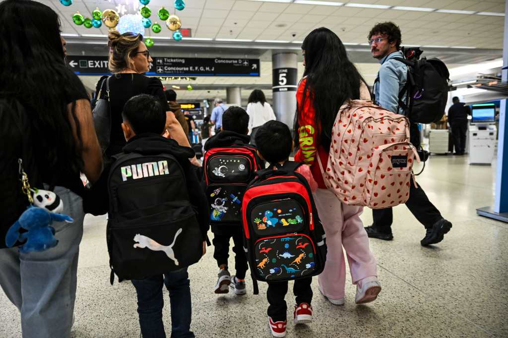 Osvaldo (derecha) cuidador de Andy (izquierda), ciudadano estadounidense de seis años, lo abraza al salir del Aeropuerto Internacional de Miami hacia Guatemala, donde se reunirá con su padre recientemente deportado, en Miami, Florida, el 4 de diciembre de 2025. (Foto, Prensa Libre: AFP).