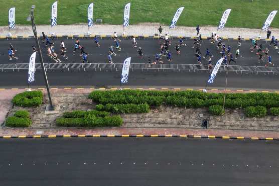 An aerial photograph shows runners participating in a marathon in Kuwait City on December 13, 2025. (Photo by YASSER AL-ZAYYAT / AFP)