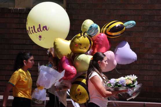 People carry balloons as they arrive for the funeral of 10-year-old Matilda, who was killed in the December 14 Bondi Beach shooting attack, in Sydney on December 18, 2025. The attack at Bondi Beach on December 14 was one of the deadliest in Australian history. (Photo by DAVID GRAY / AFP)