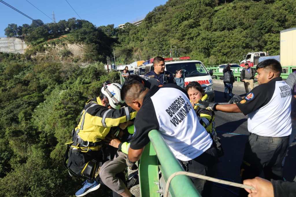 Bomberos levantan a una persona para ponerla a salvo durante el rescate y acompañamiento psicológico en puente Charcas, Mixco.