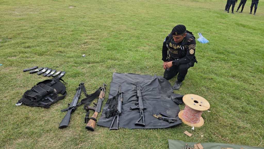Agente de la PNC frente a las armas incautadas tras ataque del cartel de Sinaloa