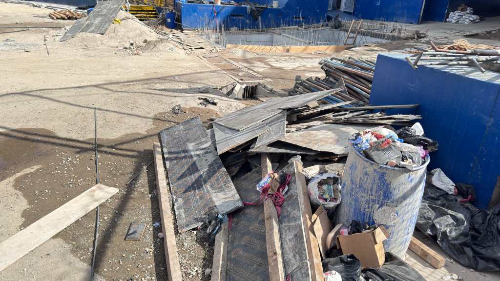 Escombros, un tonel con desechos y tubos de construcción en un área del estadio.