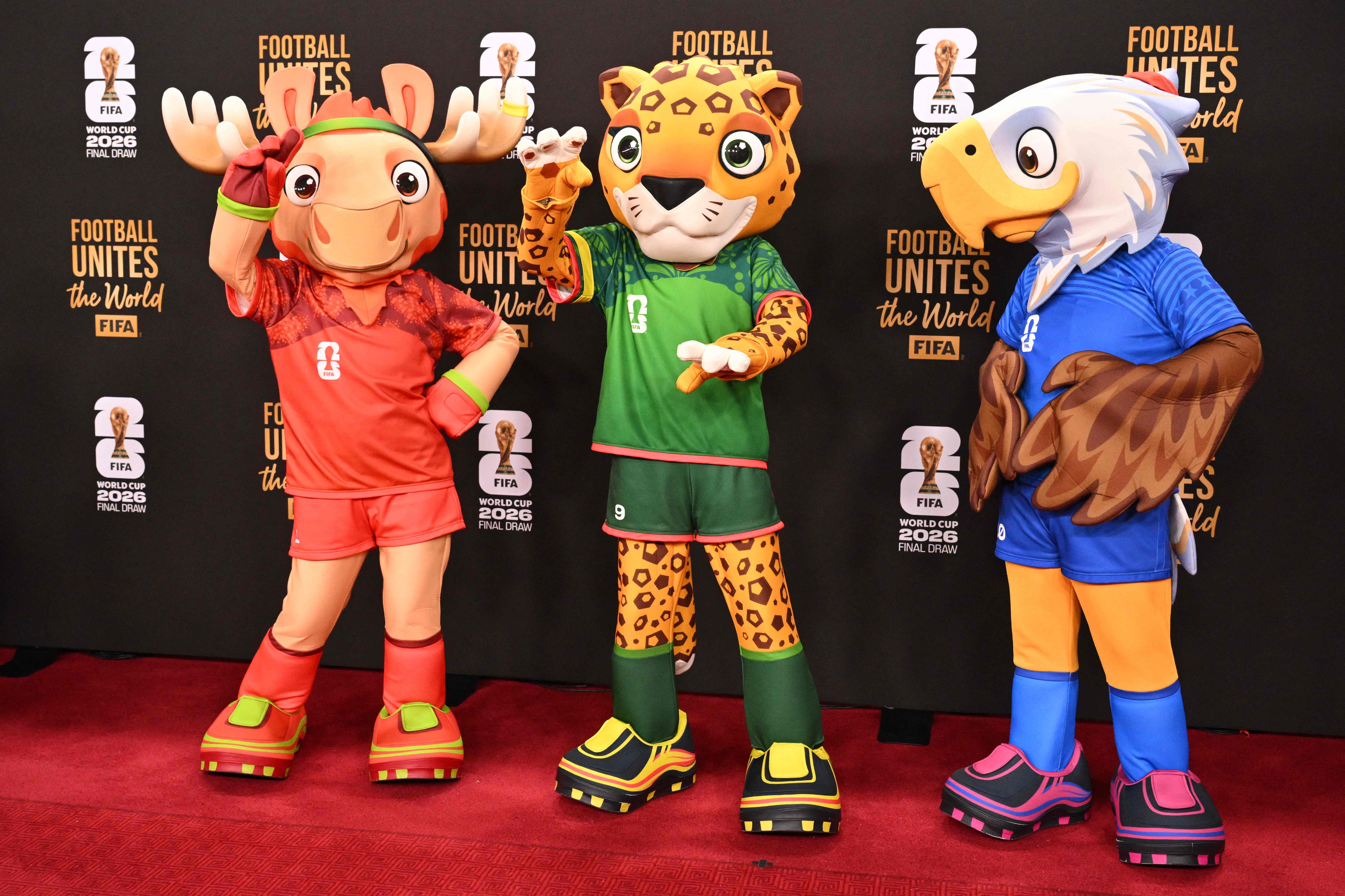 The FIFA World Cup 2026 mascots (L-R), Maple the Moose (Canada), Zayu the Jaguar (Mexico), and Clutch the Bald Eagle (US) pose on the red carpet upon arrival to attend the draw for the 2026 FIFA Football World Cup taking place in the US, Canada and Mexico, at the Kennedy Center, in Washington, DC, on December 5, 2025. (Photo by Roberto SCHMIDT / AFP)