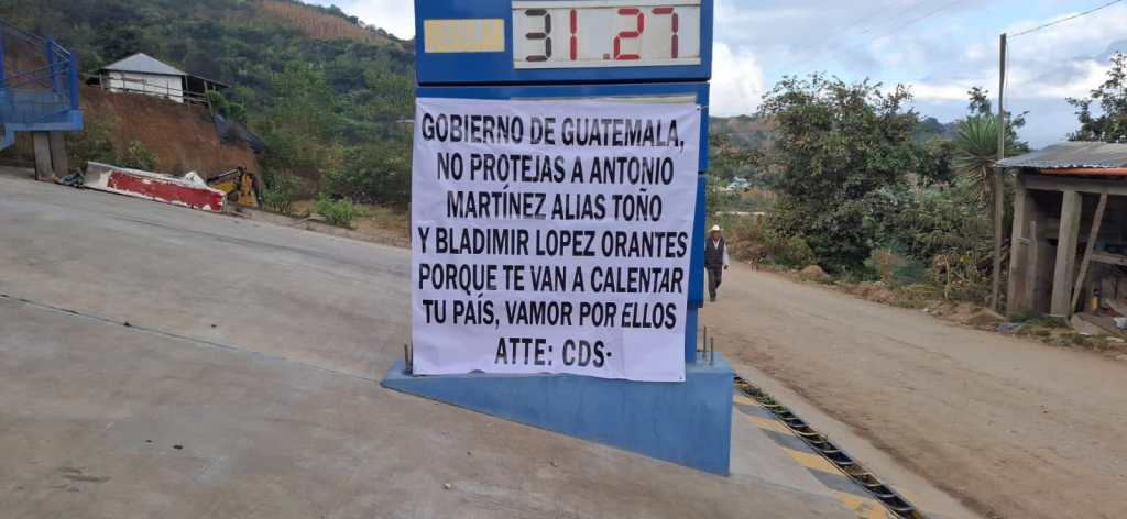 Manta colocada en un letrero de precios de gasolinera con advertencia sobre integrantes del Cártel Chiapas-Guatemala en Aldea Tuicoche.