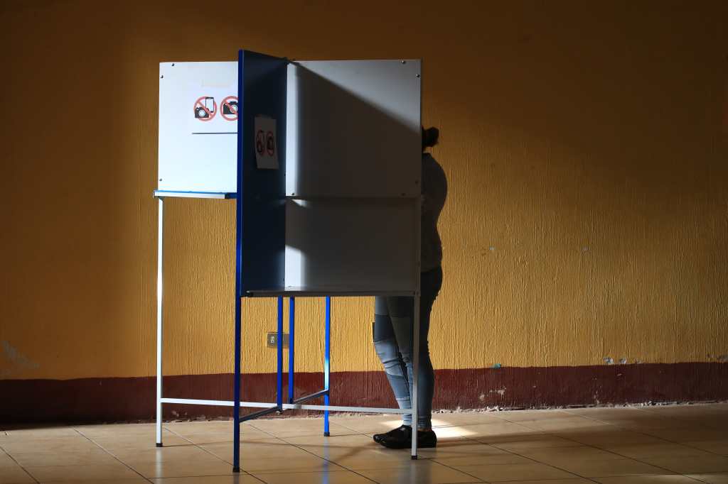 Persona emitiendo su voto en un atril durante el proceso electoral en Guatemala.
