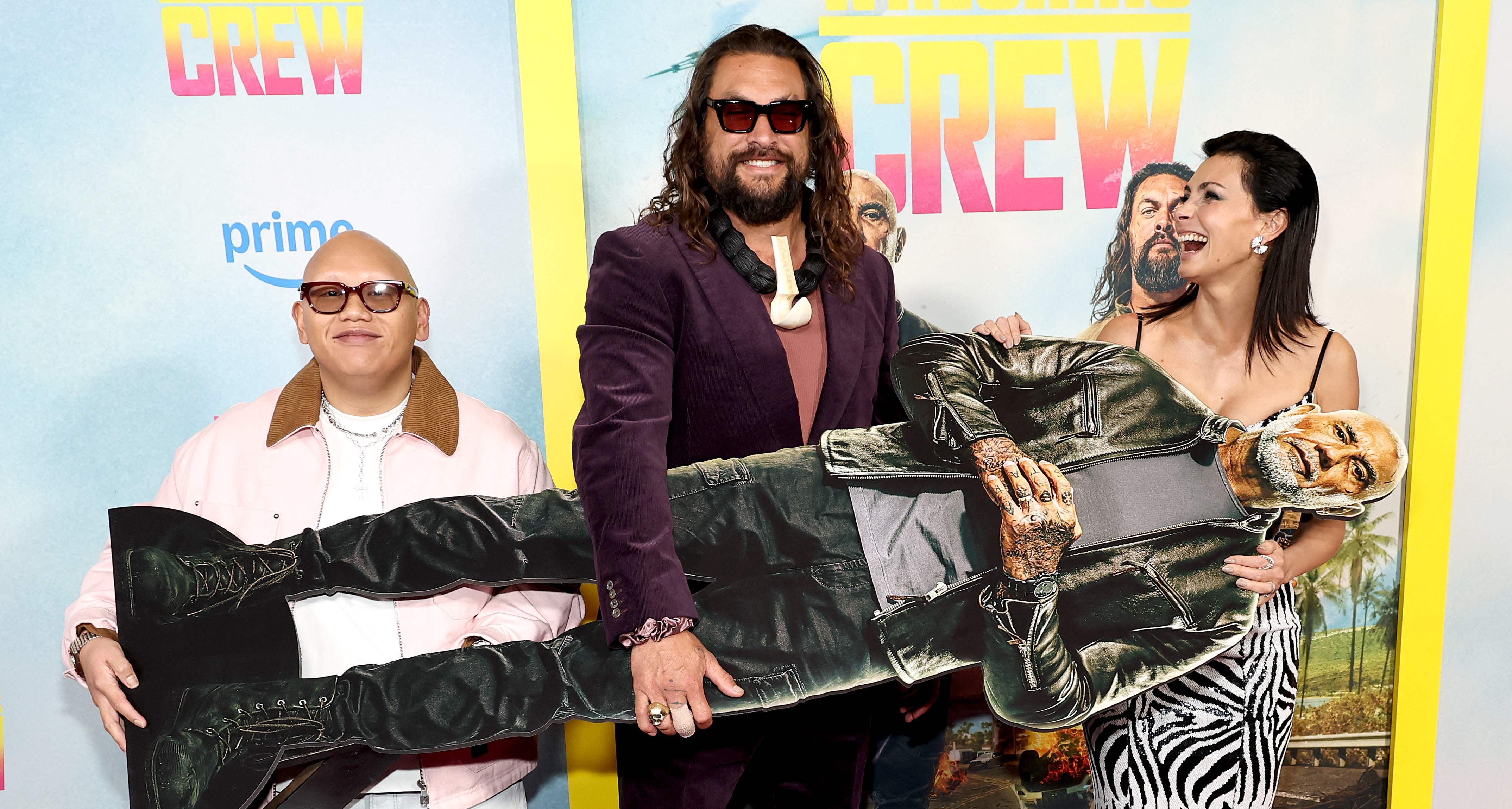 Jacob Batalon, Jason Momoa y Morena Baccarin asisten a la proyección de "The Wrecking Crew" en Nueva York.  Sostienen la imagen de Dave Bautista quie no asistió a la gala.   (Foto Prensa Libre: AFP)