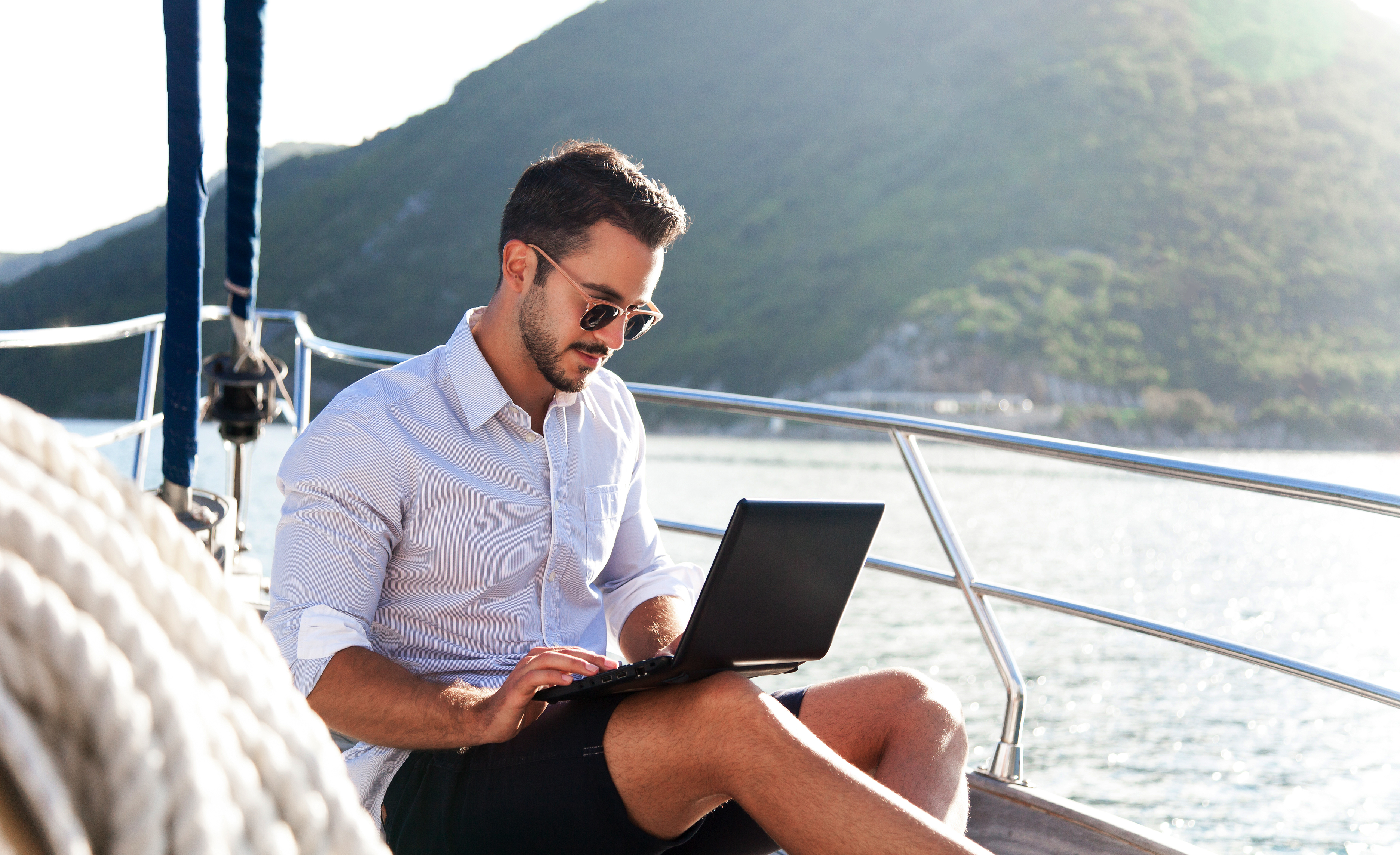 Working in travel. Man on yacht with laptop. Sea vacation on sailboat with insurance. Traveler using computer, Internet. Freelancer office workplace in silence, calmness. Successful business lifestyle