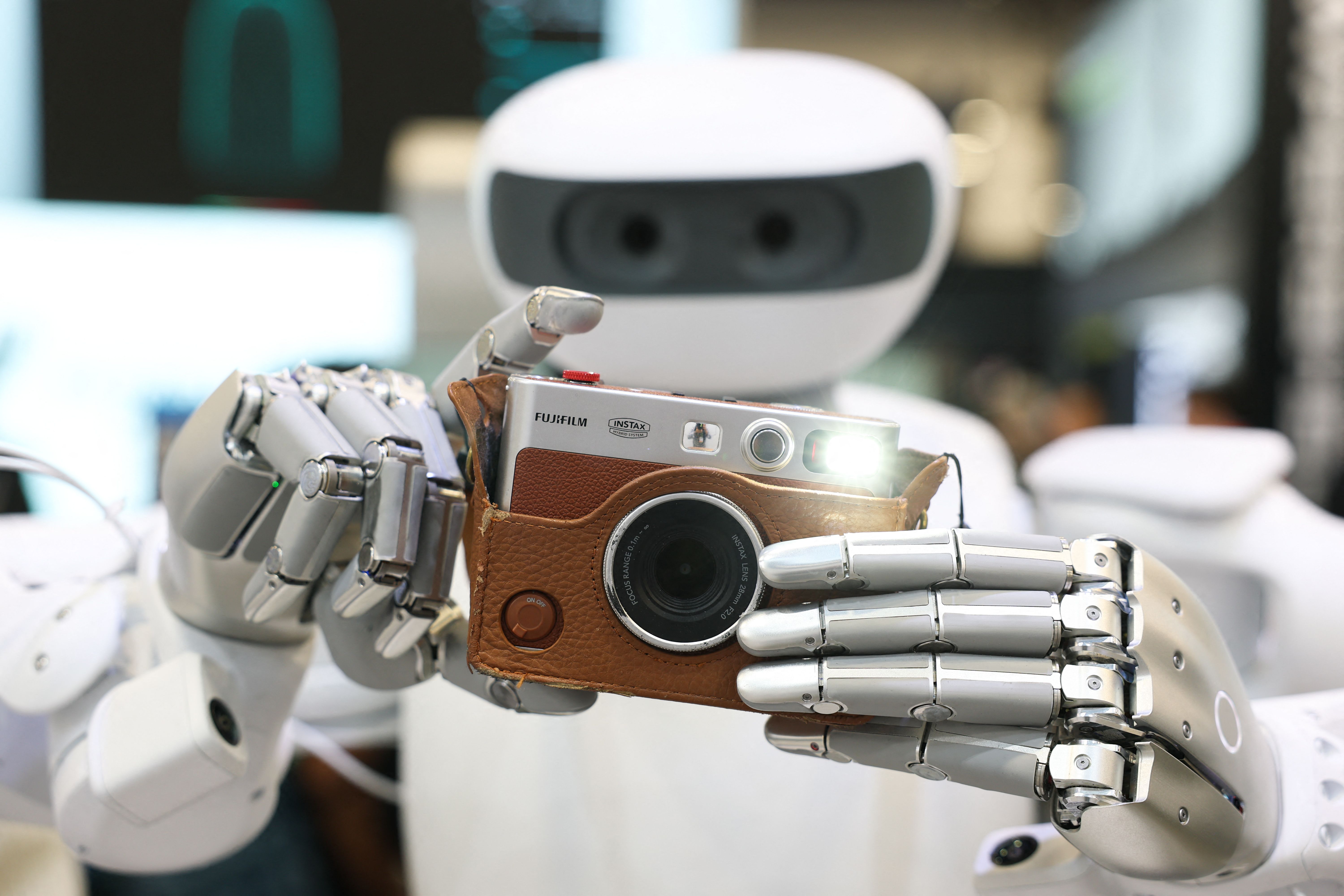El robot Sharpa toma una fotografía con una cámara Fujifilm instax durante la CES 2026. (Foto Prensa Libre: AFP)