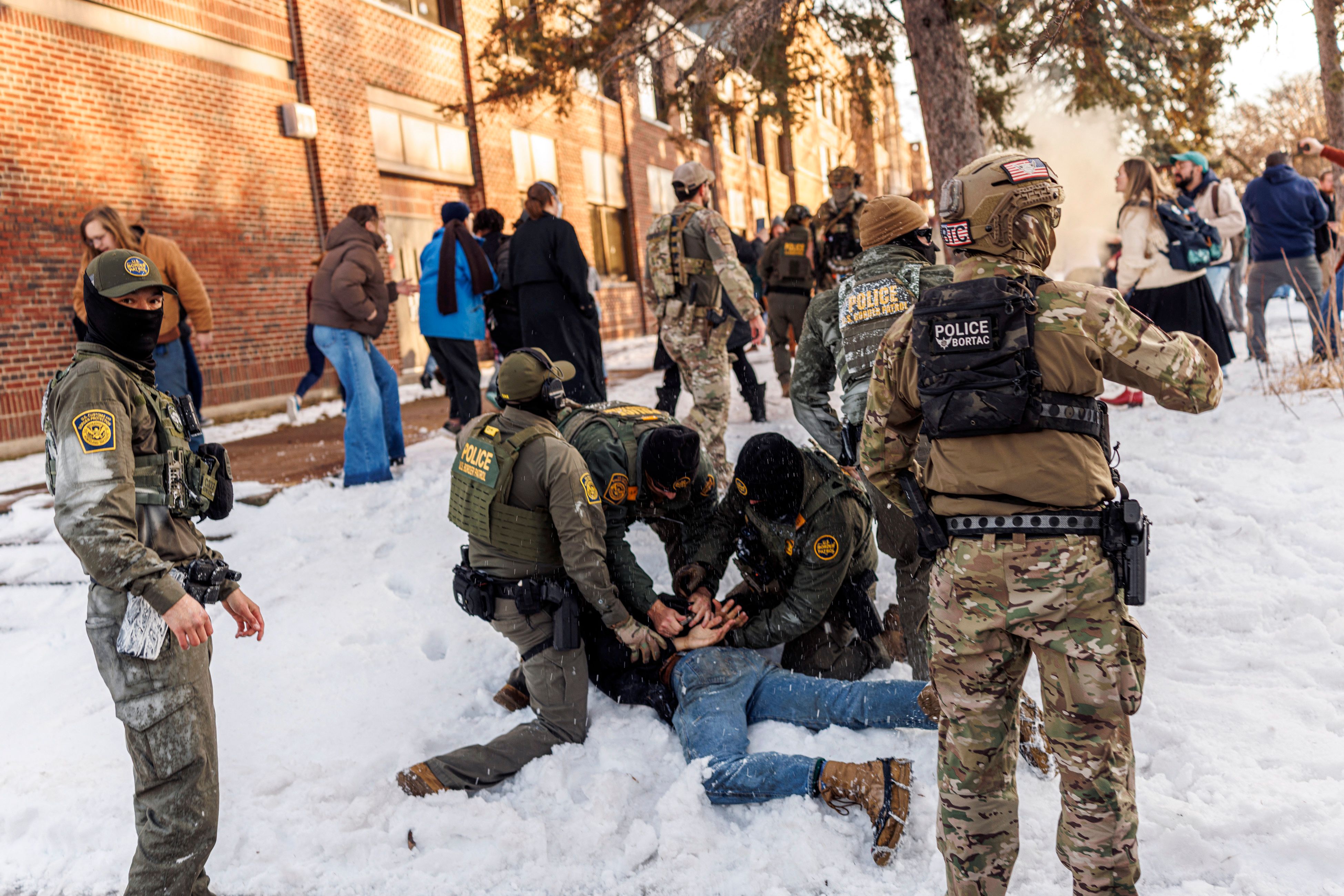 US Border Patrol agents detain a person near Roosevelt High School during dismissal time in Minneapolis, Minnesota, on January 7, 2026. An immigration officer in Minneapolis shot dead a woman Wednesday, triggering outrage from local leaders even as US President Donald Trump claimed the officer acted in self-defense. Minneapolis Mayor Jacob Frey deemed the government's allegation that the woman was attacking federal agents "bullshit," and called on Immigration and Customs Enforcement (ICE) officers conducting a second day of mass raids to leave Minneapolis. (Photo by Kerem YUCEL / AFP)