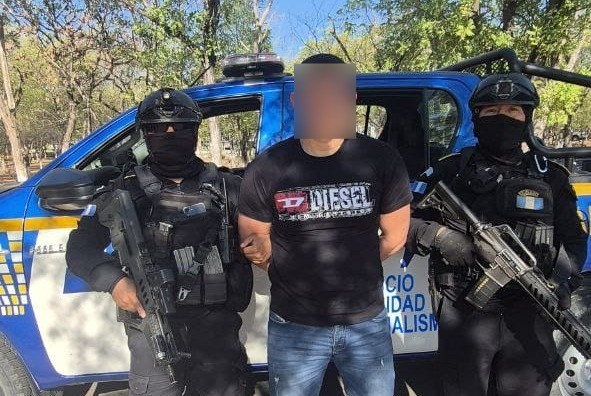 Agentes antinarcóticos custodian a Alex “C”, trasladado vía aérea hacia Ciudad de Guatemala. (Foto Prensa Libre: PNC)