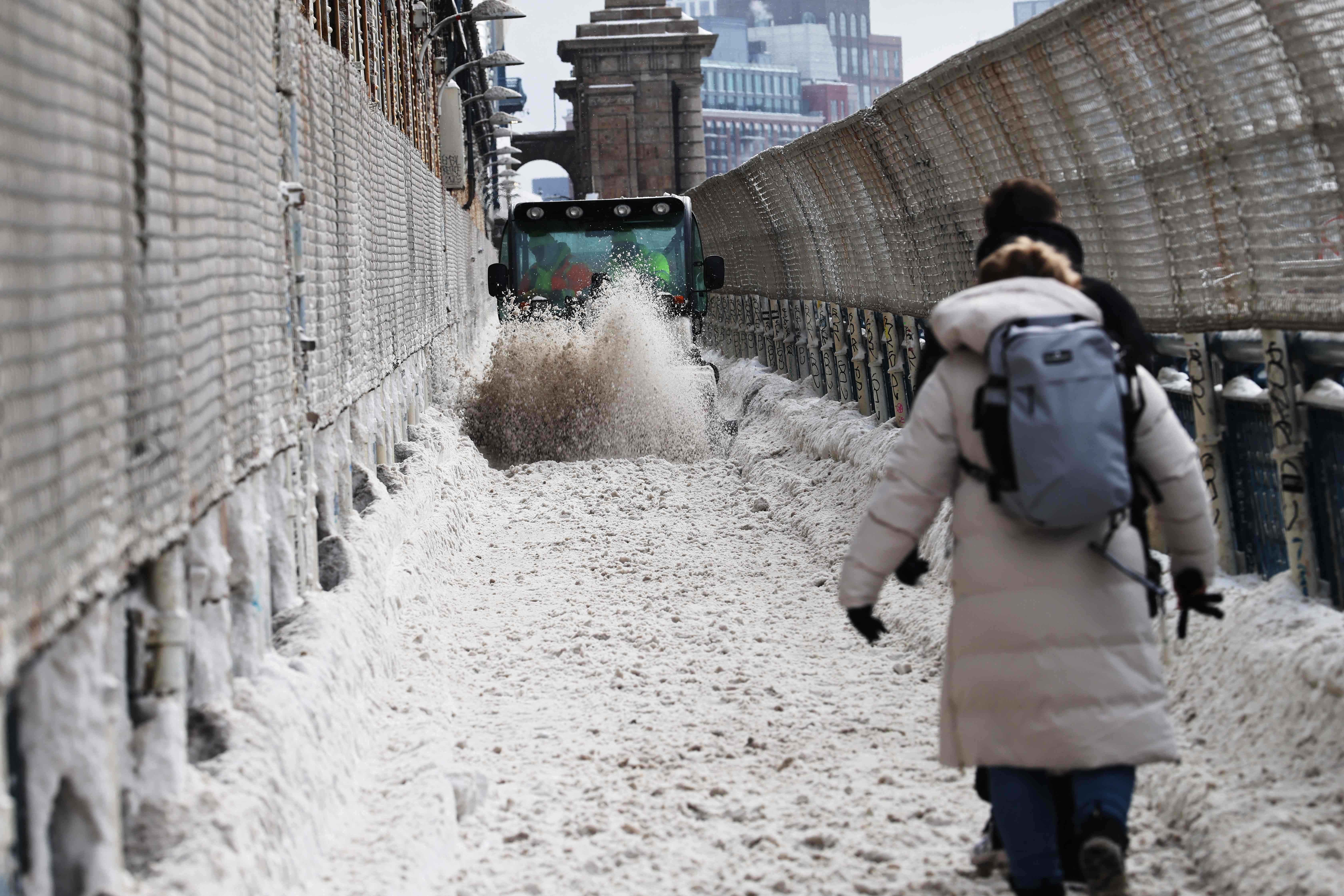 NEW YORK CITY - JANUARY 26: People walk through the snow on the Manhattan Bridge after a storm left nearly one foot of snow on January 26, 2026, in New York City. A massive winter storm has brought frigid temperatures, ice, and snow to millions of Americans across the nation. The storm has left at least 10 people dead and hundreds of thousands without power.   Spencer Platt/Getty Images/AFP (Photo by SPENCER PLATT / GETTY IMAGES NORTH AMERICA / Getty Images via AFP)