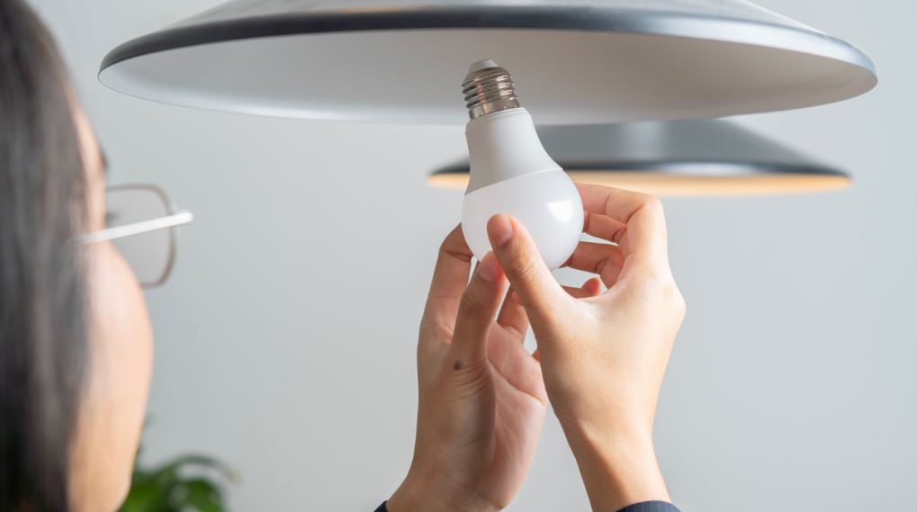 persona colocando un foco bombilla energía eléctrica tarifas