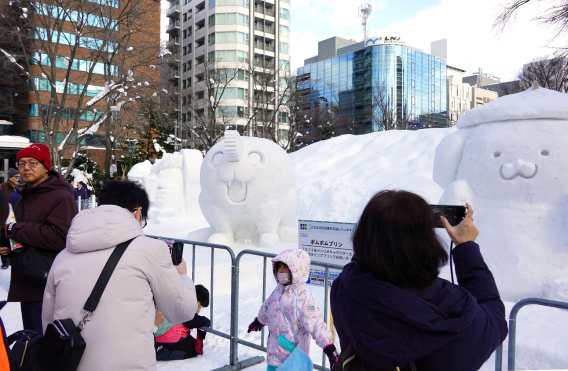 Visitors take photos and pose with snow sculptures on display at the Sapporo Snow Festival venue, which opened in Sapporo, Hokkaido on February 4, 2026. (Photo by JIJI Press / AFP) / Japan OUT