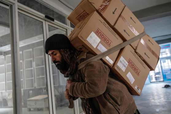 This photograph taken on February 9, 2026 shows an Afghan worker carrying pharmaceutical packages, which were imported from India, at a pharmacy in Kabul. Afghanistan's decision to overhaul its medicine market was meant to improve quality and boost domestic production, but industry specialists say the swift changes have led to a litany of problems. (Photo by Wakil KOHSAR / AFP)