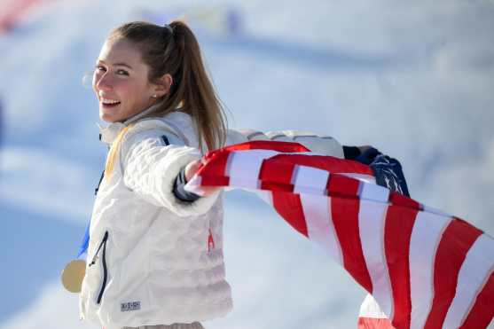 USA's gold medalist Mikaela Shiffrin celebrates with her national flag during the podium ceremony of the women's slalom event during the Milano Cortina 2026 Winter Olympic Games at the Tofane Alpine Skiing Centre in Cortina dAmpezzo on February 18, 2026. (Photo by Marco BERTORELLO / AFP)